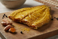 Curry-seasoned fish fillet with turmeric root and peppercorns on wooden board